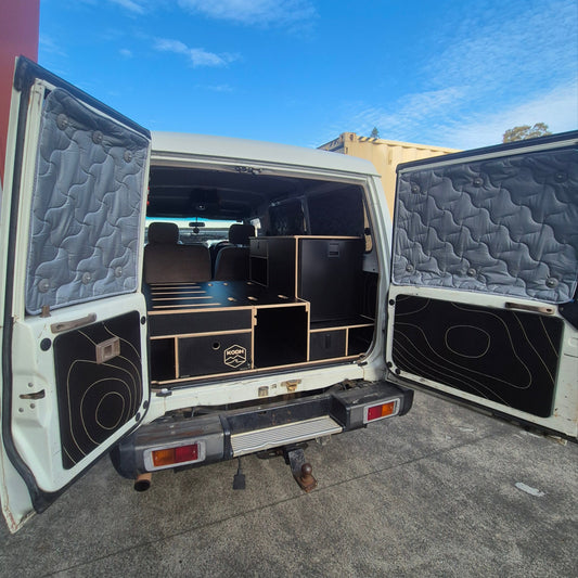 Open cargo area of a vehicle with storage compartments and a quilted lid.